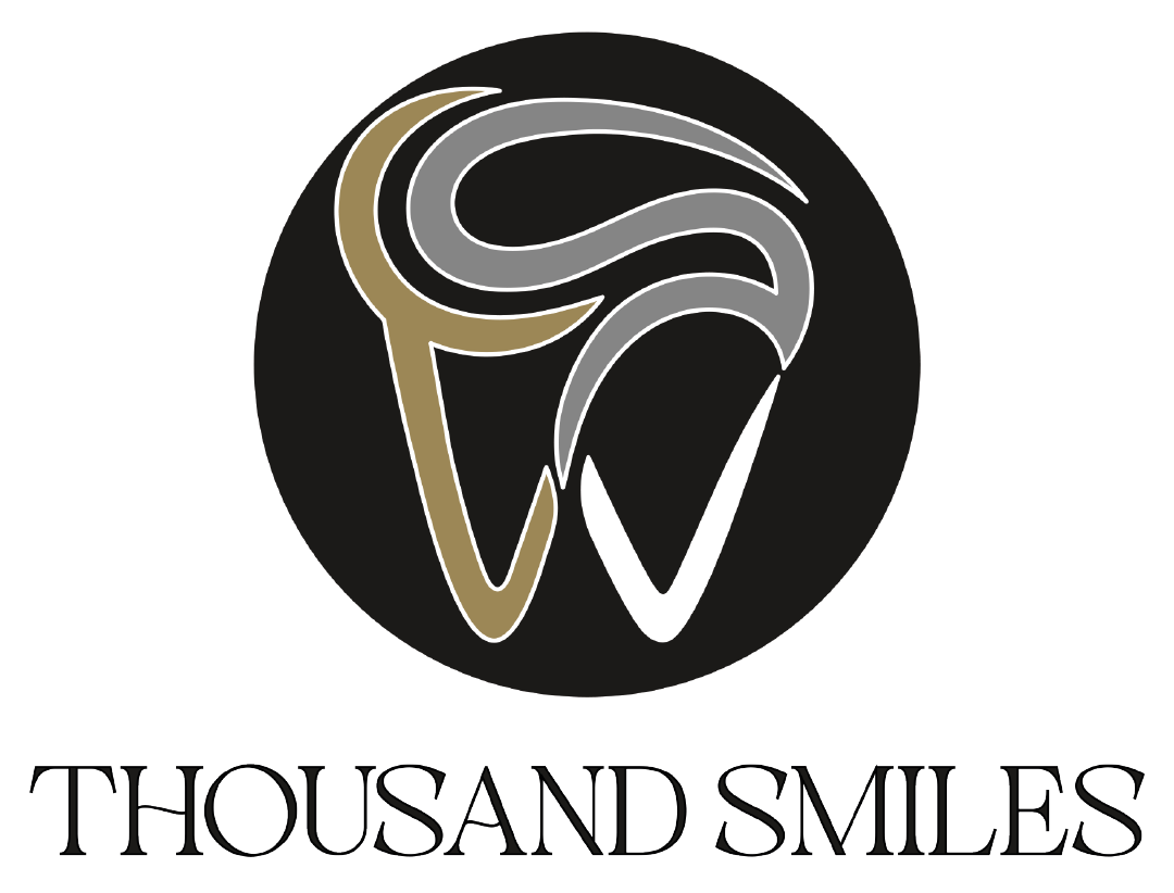 Thousand Smiles primary emblem — black disc with a thin light ring containing an intricate tooth-shaped monogram drawn in interwoven gold, silver and white strokes, with THOUSAND SMILES set in a thin engraved classical serif beneath
